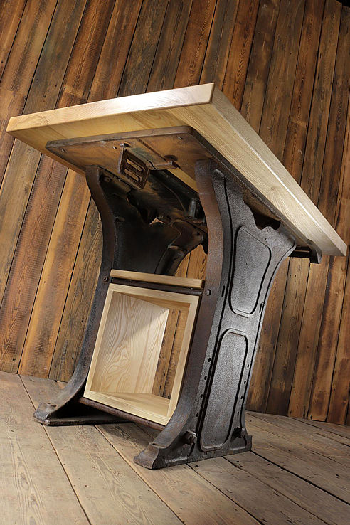 a fine table with a small footprint with a solid timber top on industrial cast iron legs and a wood lined recess