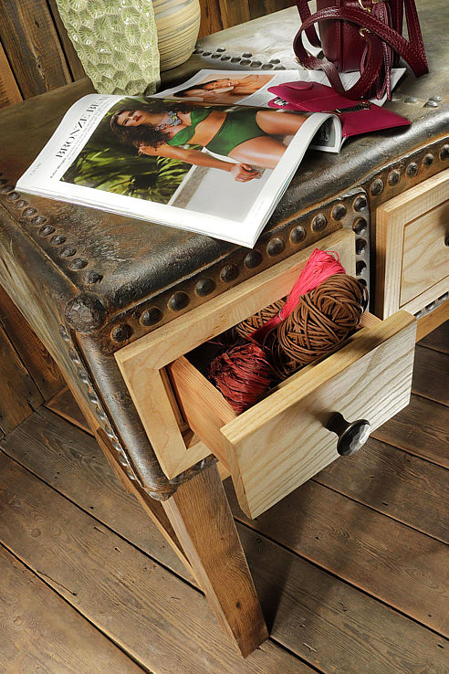 the tank table made from a reclaimed rivetted water tank inset with drawers on a rustic timber frame