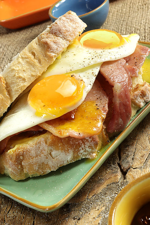 a delicious double fried egg and bacon sandwich on a green platter