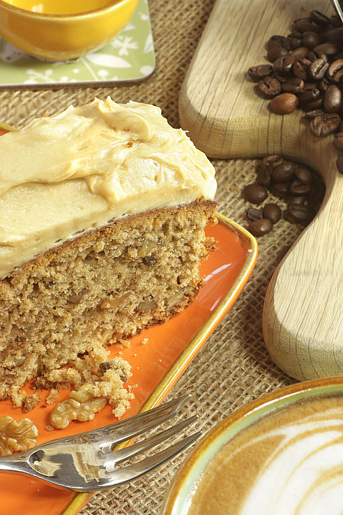 a creamy slice of coffee cake beside a cappucino coffee