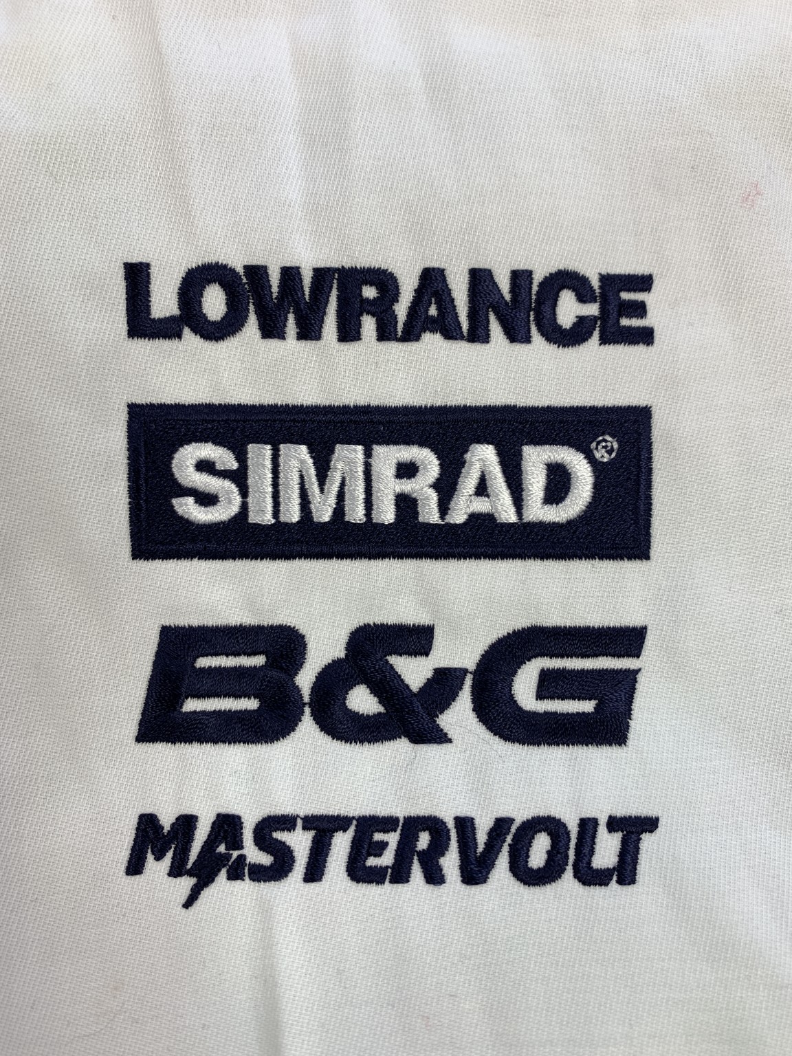 Lowrance, Simrad, B and G and Mastervolt logos embroidered on white fabric