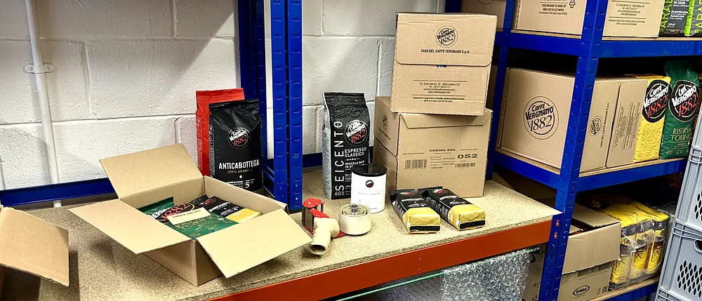 The packing bench at Crema Aroma: an open order, Caff&egrave; Vergnano bags and cartons of stock on the racking