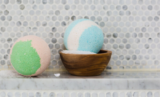 two multi-coloured bath bombs on a shelf